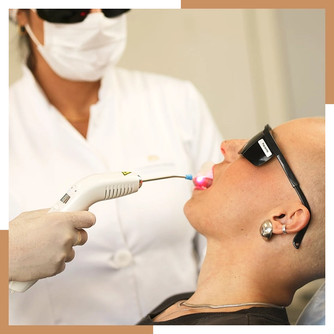 Sessão de laserterapia: profissional aplica laser na boca de uma paciente oncológica