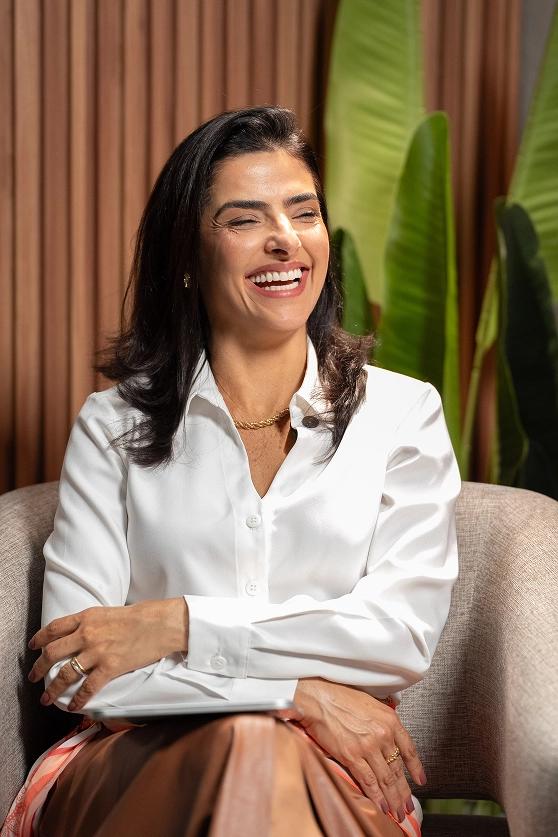Dra. Lidiana sorrindo em poltrona durante o podcast